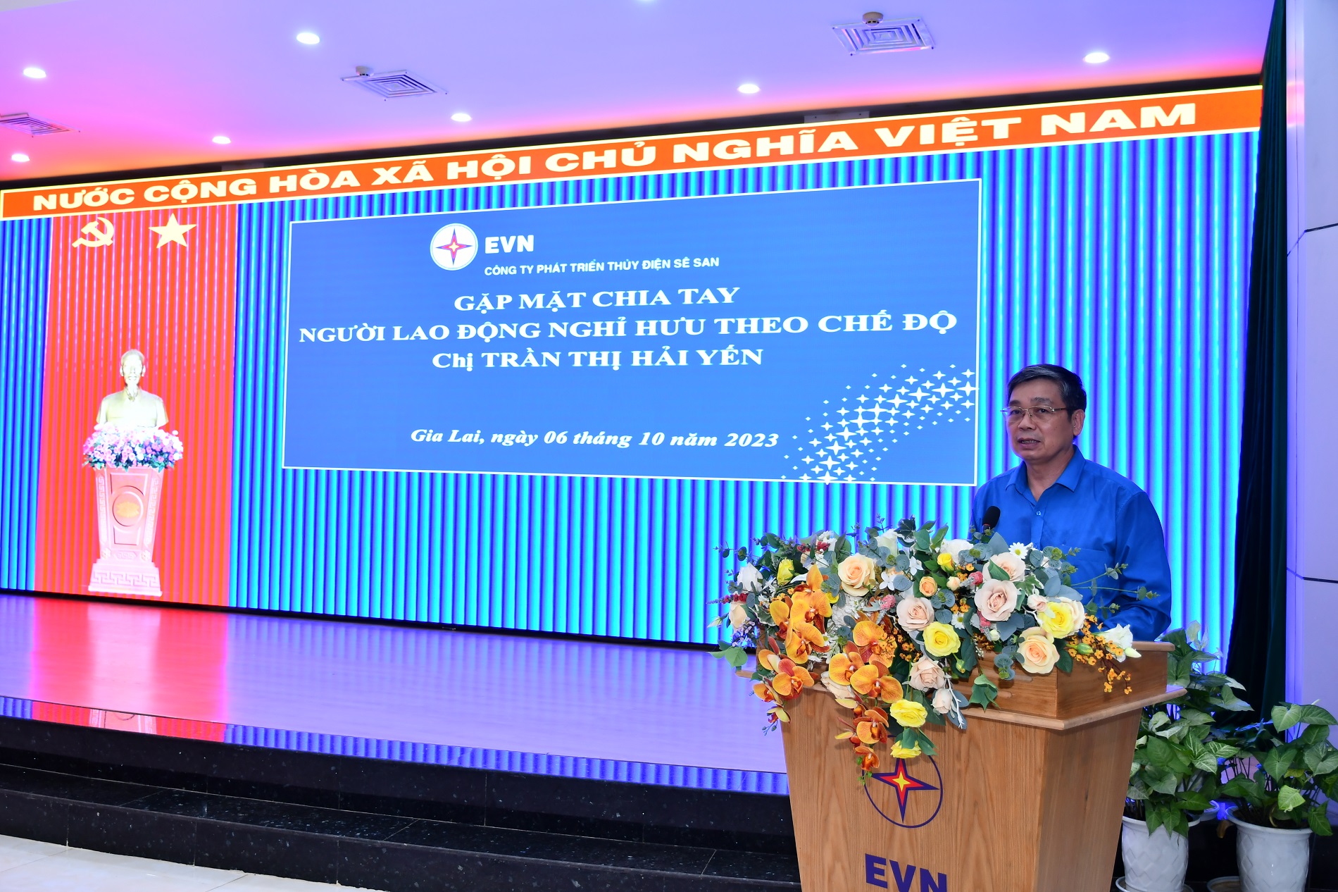 A person standing at a podium with flowersDescription automatically generated